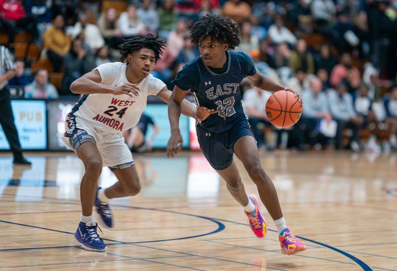 Oswego East's Jehvion Starwood (22) dribbles the ball against West Aurora's Terrence Smith (24) during a basketball game at West Aurora High School on Friday, Jan 27, 2023.