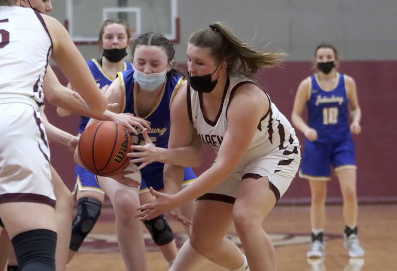 Marengo’s Addie Johnson, right, scrambles for the ball with Johnsburg’s Bella Saxelby, center,  during girls varsity basketball action in Marengo Thursday night.