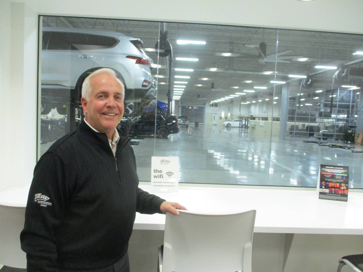 Terry D'Arcy stands by a window in the customer service area looking out to the 38-bay service area of his new Hyundai dealership.