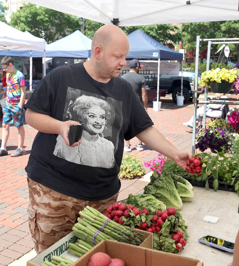 Kris Waramoski, from Channahon, picks out some radishes at the Theis Farm Market booth Thursday, June 2, 2022, during the first DeKalb Farmers Market of the season at Van Buer Plaza in Downtown DeKalb.