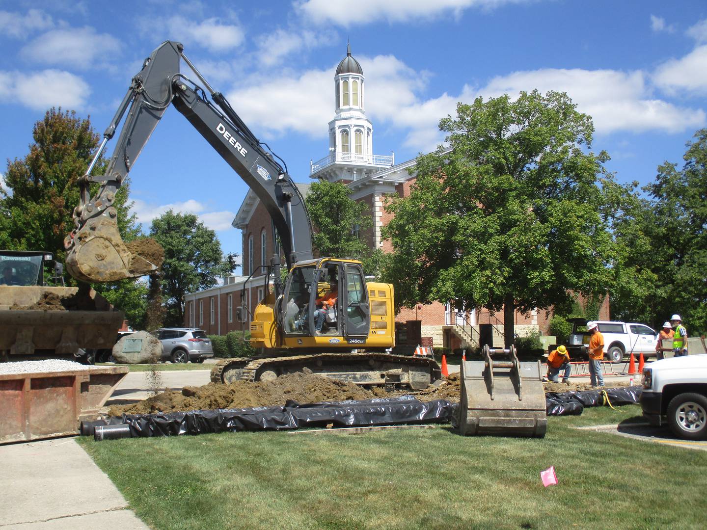 An excavator loads dirt into an end-loader's shovel at the Kendall County downtown Yorkville office campus on Aug. 30, 2023. The site's parking areas, sidewalks and driveways are to be reconfigured.