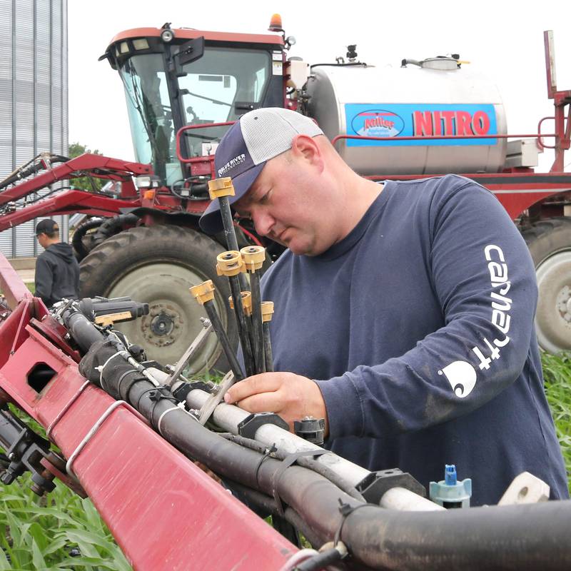 Farmer Mike Schweitzer changes the nozzles on the sprayer tractor in one of his fields Friday, June 16, 2023, on his farm in Malta.