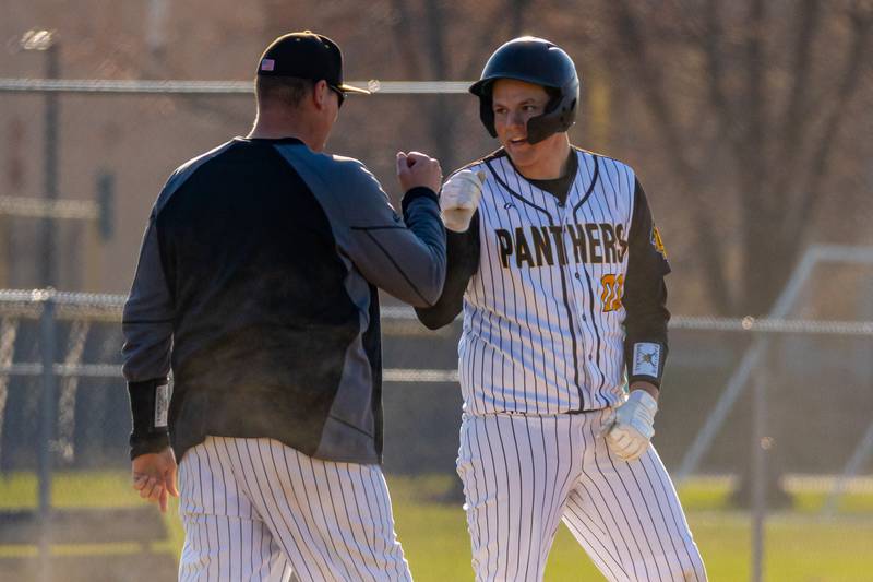 Jaden Stoddard (00) of Putnam County fist bumps coach after making it to third base on Tuesday, April 8, 2025 at Putnam County High School in Granville.