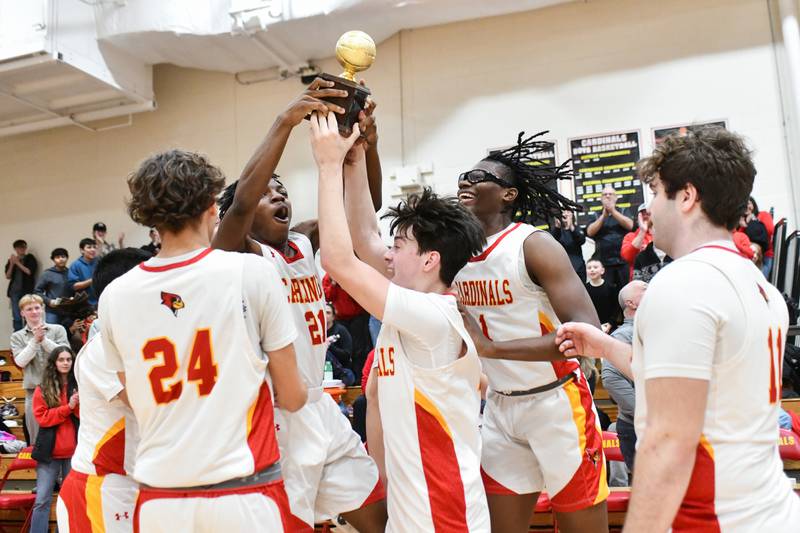 St. Anne's Jaqorri Wyatt, left, Matthew Langellier, center, and Chris Link rush to hoist the River Valley Conference Championship trophy with teammates Friday, Feb. 14, 2025, after the Cardinals' 70-38 victory over Beecher.