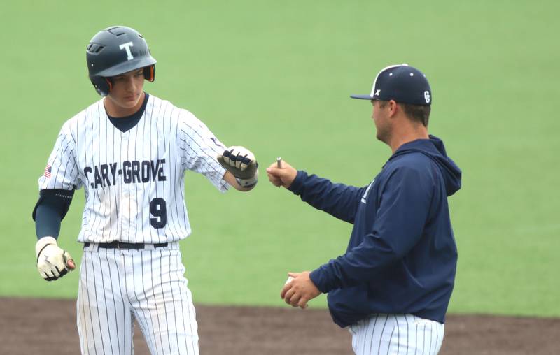 Cary-Grove’s Ricky Barnes is greeted after arriving safely at first base with a single against Triad in IHSA Class 3A Third Place Game baseball action at Slammer Stadium in Joliet on Saturday, June 14, 2025.