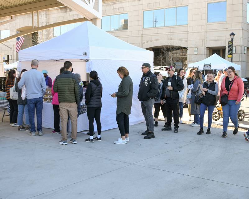 People wait in line at the Scone House tent during the Wheaton French Market in downtown Wheaton on Saturday April 13, 2024.