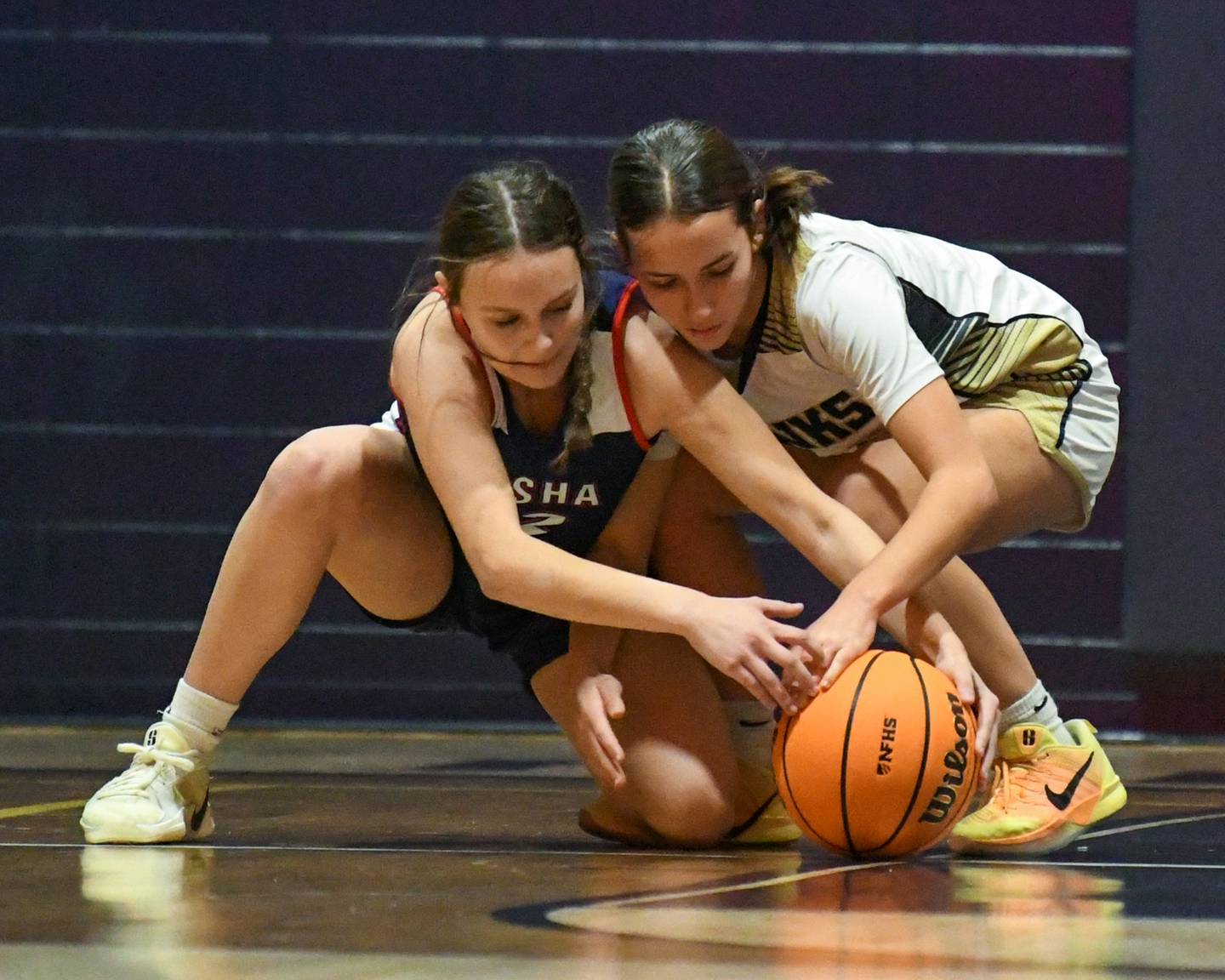 Hiawatha's Mallory Banks, right, and Our Lady of The Sacred Heart Jackie Whalen battle for a loose ball during the game on Monday Dec. 22, 2025, held at Hiawatha High School.