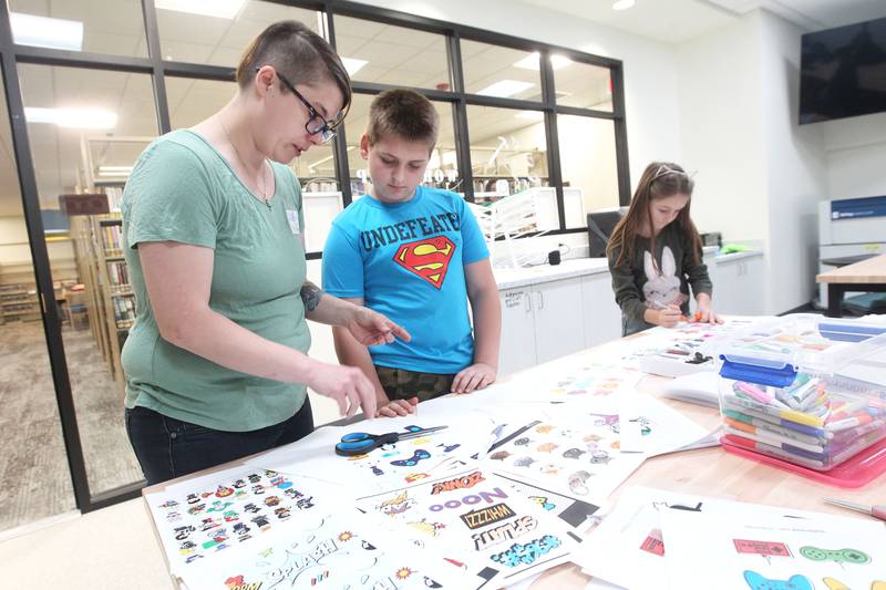 Krystal Loder, of Lake Villa, IT and workshop associate, helps Samuel Molnar, 12, of Ingleside, make a Shrinky Dinks craft with his sister, Emily, 9, close by in the Workshop on Saturday, May 13, 2023, during the Antioch Public Library District Open House in Antioch. The Workshop is a new addition to the library.