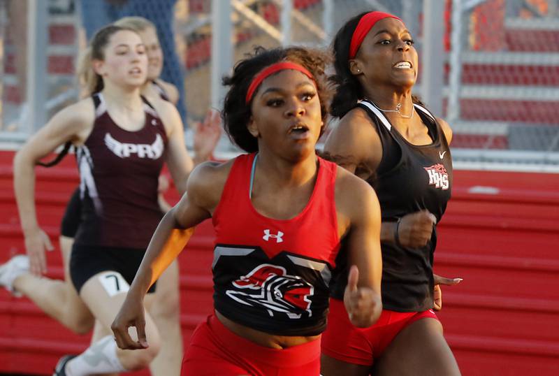 Huntley's Alexandria Johnson chases Auburn’s Essence Horton-Graves as she races to third place in the 100 meter dash Friday, May 10, 2023, during the IHSA Class 3A Huntley Girls Track and Field Sectional at Huntley High School.