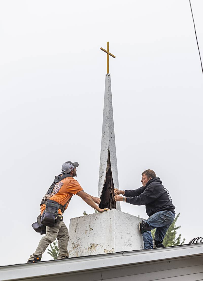 Adam Benford (left) and Keith Persico of Boss Roofing peel back the aging wood on the steeple on the former Lincoln Ave. Church of God Wednesday, Sept. 13, 2023. The cross will be saved and given to the now Grace Point Church in Dixon.