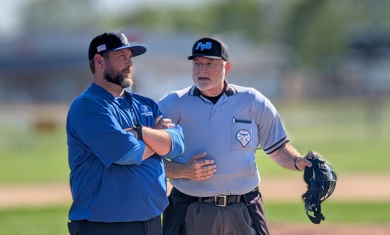 Woodstock baseball coach Ian Rago listens as the home plate umpire explains a call during the Blue Streaks' Kishwaukee River Conference game against Harvard on Tuesday, May 13, 2025, in Harvard.