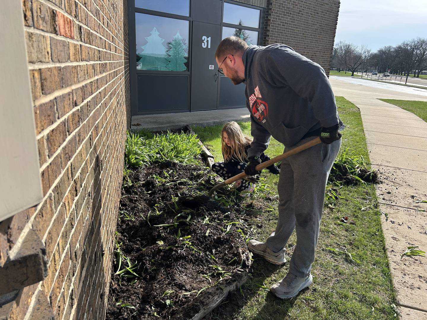 Oregon Elementary Principal Ryan Huels and his daughter, Brynnley, 9, help clear plants near Etnyre wing gym entrance making it ready for new plants on Saturday, April 5, 2025.