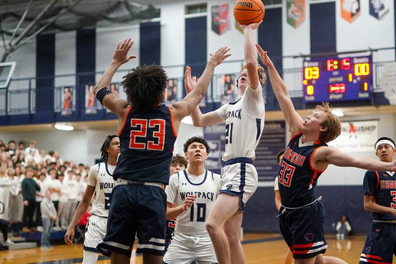 Oswego East's Andrew Pohlman (21) shoots a floater in the lane over Oswego’s Dasean Patton (23) during a basketball game at Oswego East High School on Saturday, January 14, 2017.