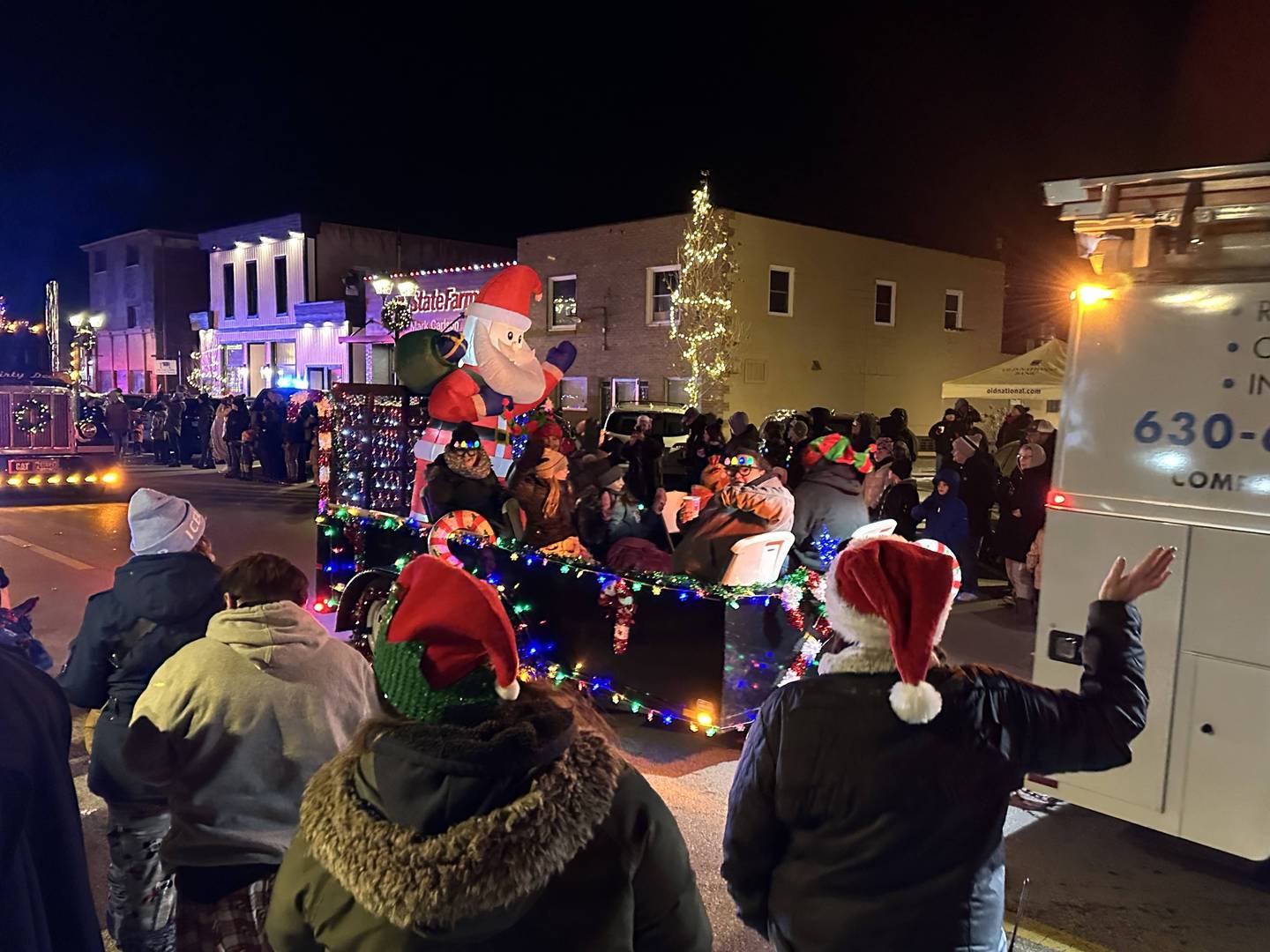 Spectators wave at passing floats in the 23rd annual Jingle Bell Parade during the Genoa Area Chamber of Commerce's annual Celebrate the Season holiday event on Dec. 6, 2024, in downtown Genoa.