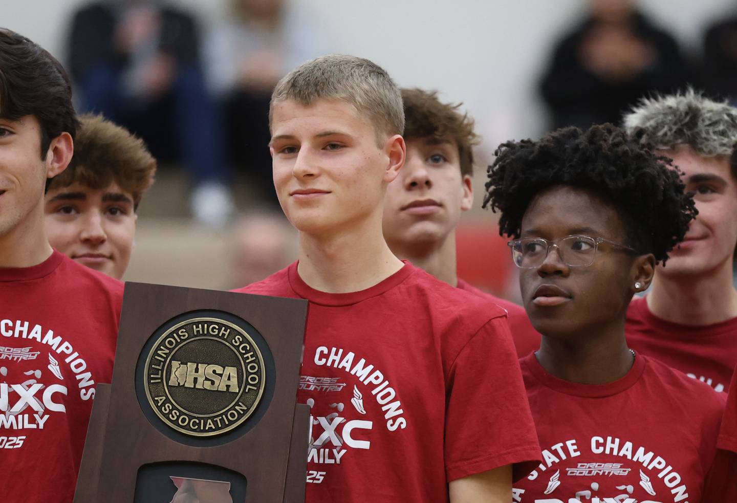 Plainfield North’s Tommy Czerwinski holds the 2025 Class 3A cross country state championship trophy while being honored at halftime during a basketball game against Plainfield East on Tuesday, Dec. 9, 2025 in Plainfield.