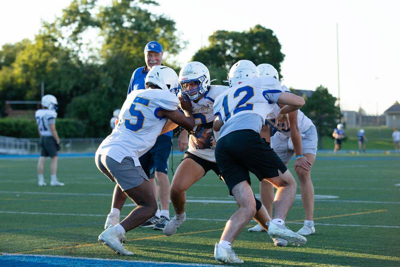 Niko Gamauf, right, and Eli Cook hold back defensive end Anderson Fitzpatrick, middle, during practice at Wheaton North on Thursday, Aug. 11, 2022.