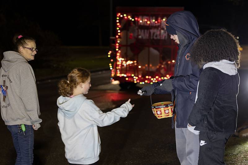 Cooper South, the student council vice president at St. Andrew's School, hands out candy canes Sunday, Nov. 28, 2022 at Centennial Park in Rock Falls as part of Rock Falls Tourism’s tour of holiday lights.