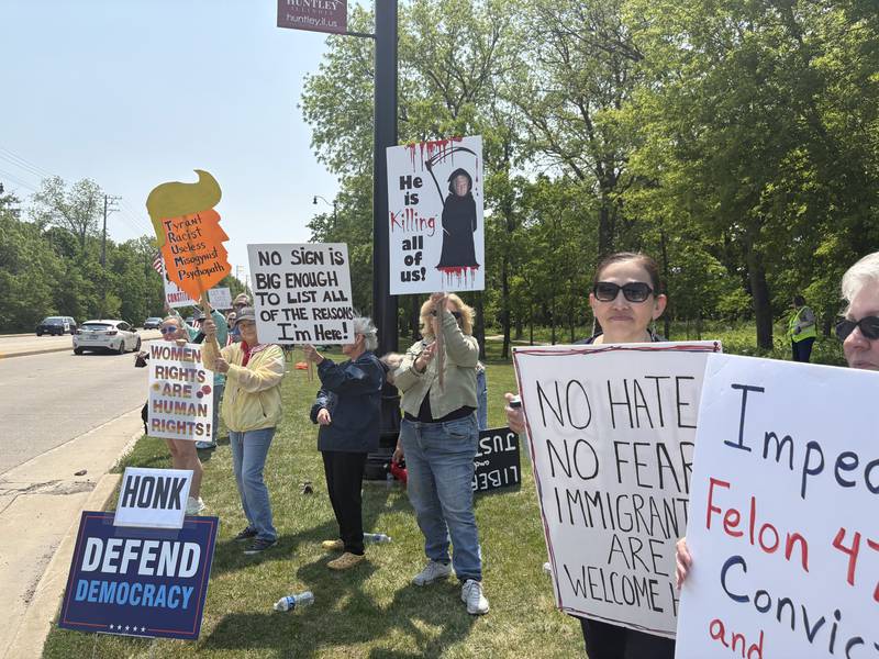 People hold up signs during a rally against President Donald Trump in Huntley May 31, 2025.
