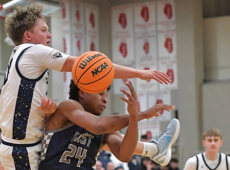Oswego East’s Dshaun Bolden (24) takes a hard foul from New Trier’s Elton Jaegerskog during a When Sides Collide Shootout game on January 24, 2026 at Benet Academy in Lisle.