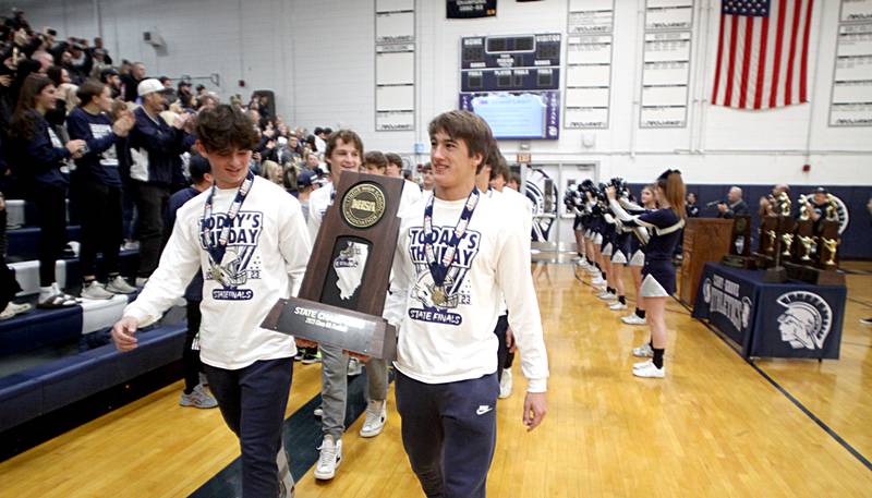 Players march into the main gym during a celebration of the IHSA Class 6A Champion Cary-Grove football team at the high school Sunday.