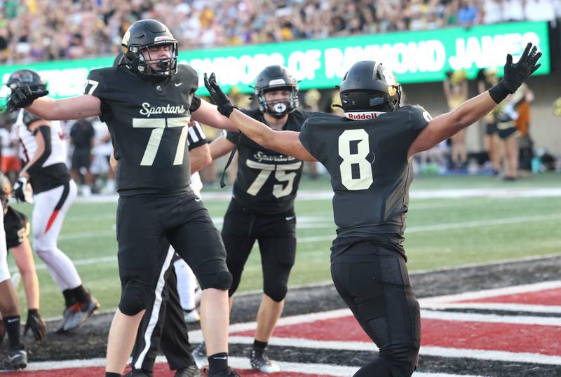 Sycamore's Michael Chami (left) and Owen DePauw celebrate with Diego Garcia (right) after he scored the games first touchdown during the First National Challenge game Friday, Aug. 25, 2023, in Huskie Stadium at Northern Illinois University in DeKalb.