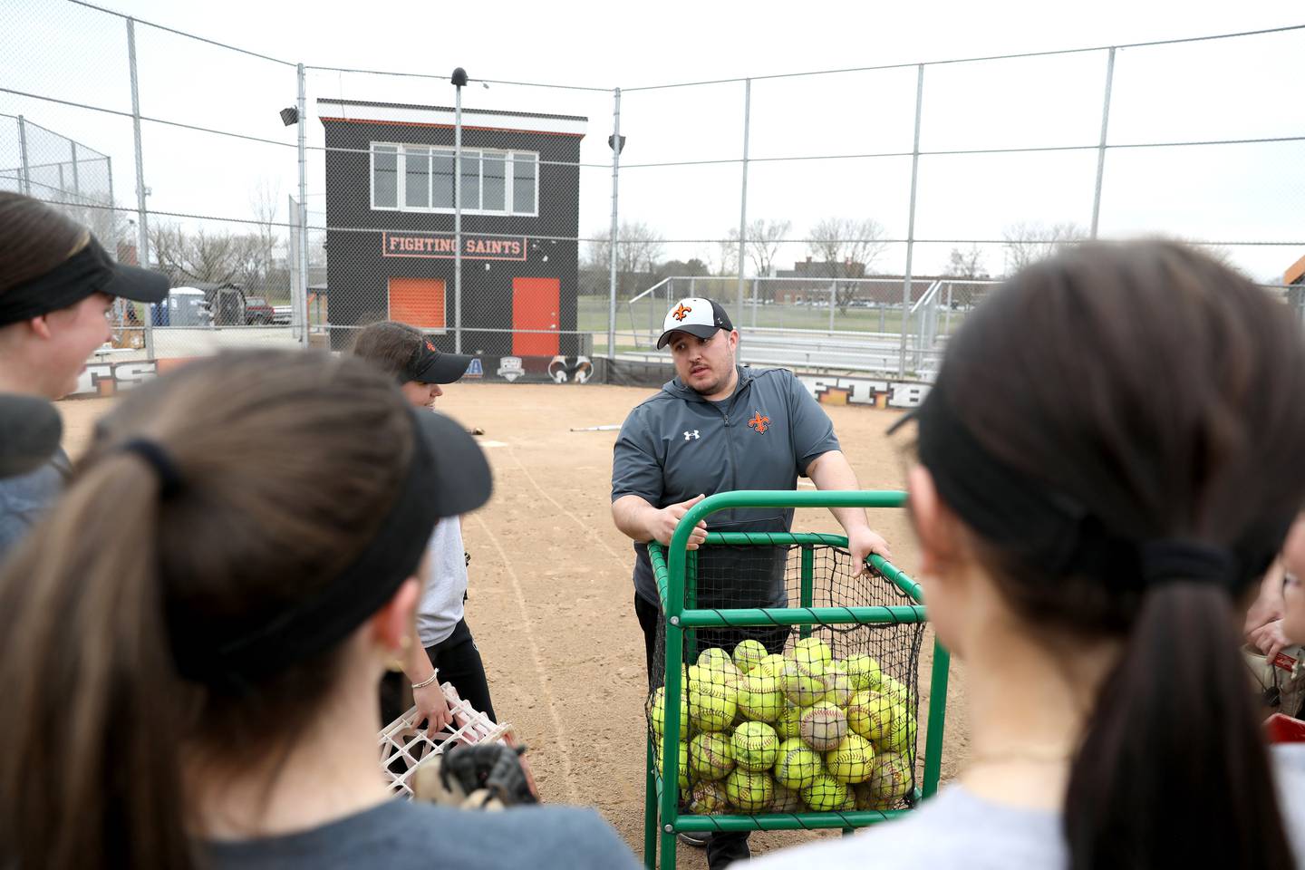 Assistant Coach Max Payleitner, a graduate of St. Charles Schools, works with the St. Charles East varsity softball team during a recent practice at the school.  Payleitner is also a teacher in St. Charles School District 303.