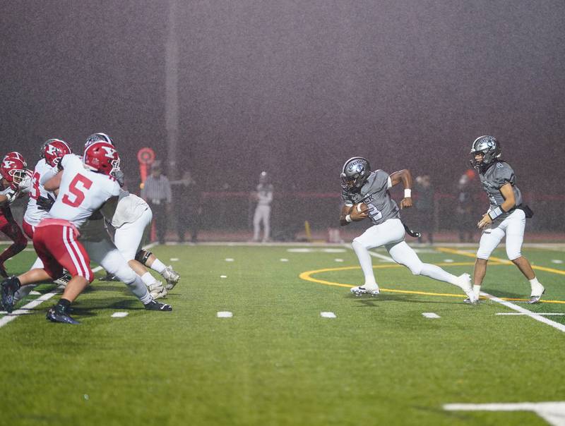 Oswego East's Jasiah Watson (13) carries the ball against Yorkville during a football game at Yorkville High School on Friday, Oct. 13, 2023.