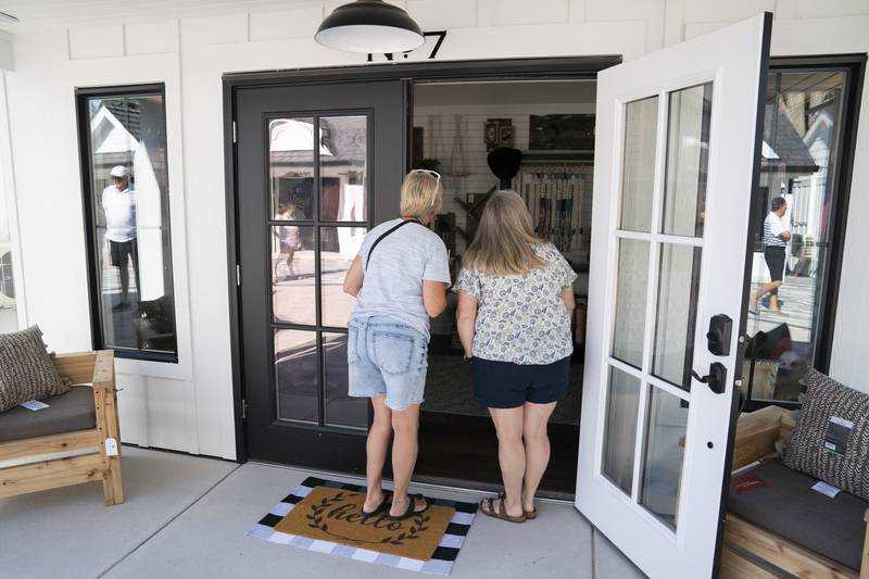 Annette Korstanje and Nancy Kruse, both of McHenry, get a sneak peak of the tiny store Lumber & Twine before it opened during the grand opening and ribbon cutting of the new McHenry Riverwalk Shoppes in downtown McHenry on Friday, July 21, 2023.