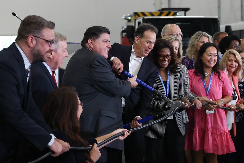 Governor JB Pritzker, center left, and Marc Bedard, CEO of Lion Electric, cut an electric cord in place of a ceremonial ribbon at the grand opening of the Lion Electric manufacturing facility on Friday, July 21st, 2023 in Joliet.