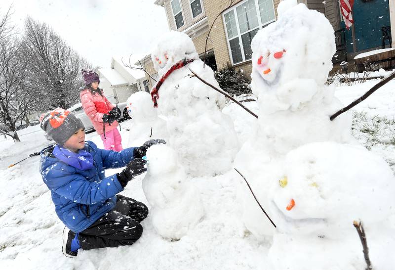 Ten-year-old Liam Cannon and his 7-year-old sister Kenzie create a snowman family in their front yard during a major snowstorm in Yorkville on Tuesday, Jan. 9, 2023.