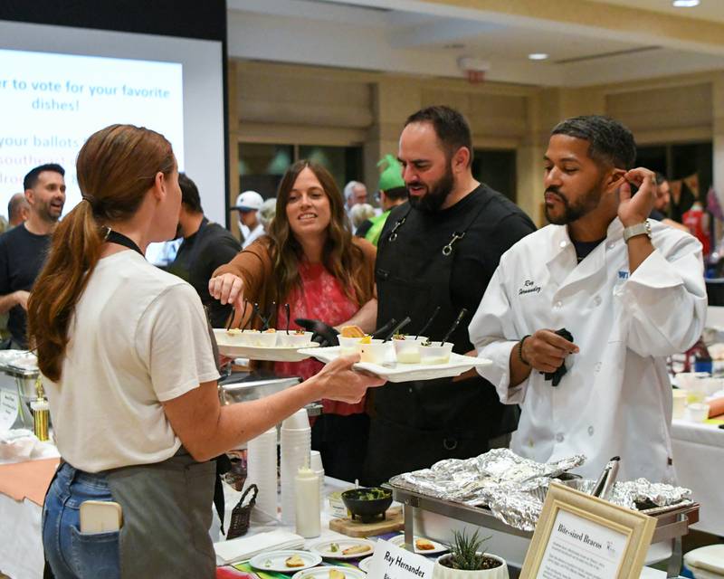 Ashley Murcia hands out samples to participants, inviting them to sample the remaining turtle cheesecake as well as a salted caramel dessert on Saturday, Aug. 9, 2025, during the 21st annual CASA DeKalb County's Men Who Cook fundraiser held at Northern Illinois University's Barsema Alumni and Visitors Center.