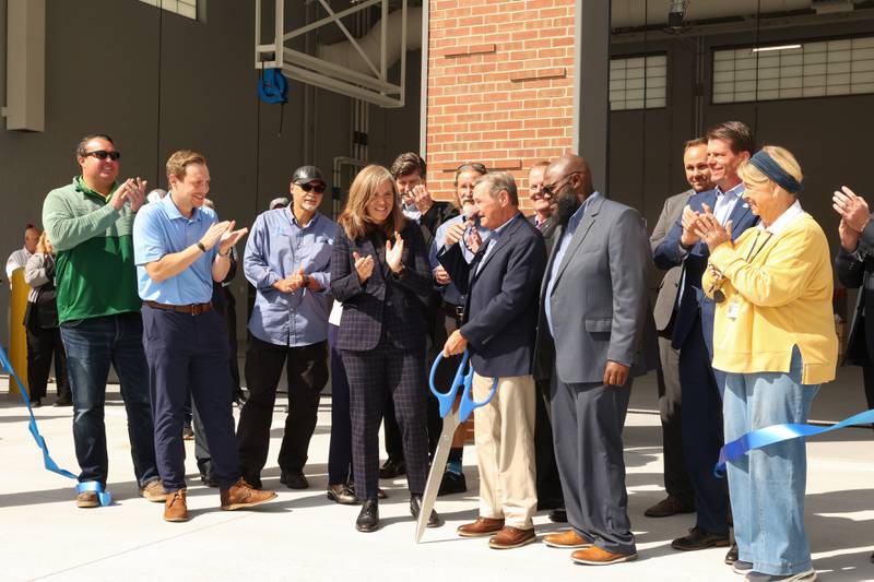 River Valley Metro Chairman Mark Argyelan, center, finishes cutting the ribbon next to CEO Siron Sims, right of center, and Illinois Transportation Secretary Gia Biagi, left of center, during the grand opening ceremony for the new bus maintenance facility on Tuesday, Aug. 26, 2025. Numerous local officials and River Valley Metro staff were on site for the unveiling.