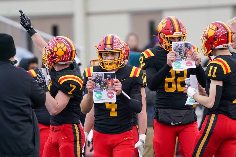 Batavia's Bodi Anderson (4) and Nate Morman (82) celebrate a victory over Downers Grove North by holding up an online prediction that had Batavia at a 28% chance to win their class 7A quarterfinal playoff football game at Batavia High School on Saturday, Nov. 16, 2024.