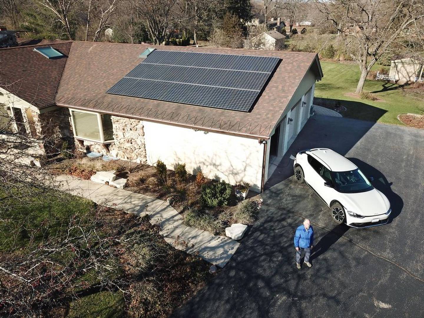 Peter Goor stands outside his Deer Park home that has solar panels on the roof. He is charging his EV car with power generated by the solar panels.