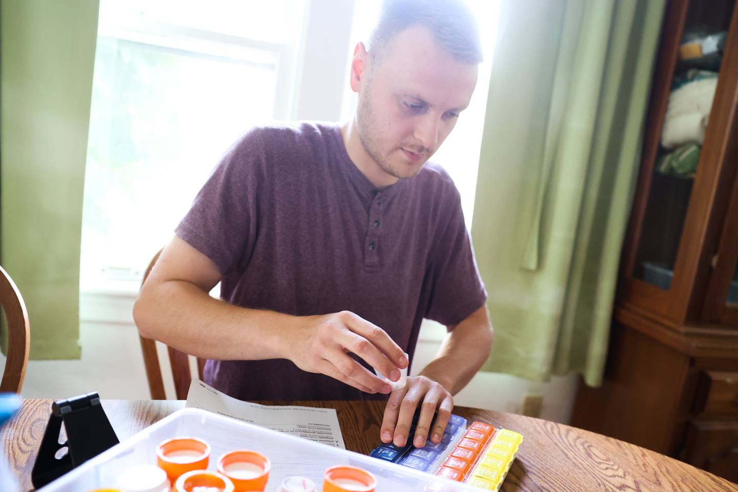 Sean Flannery prepares the evening medicine for his father, Tim. Nearly a year after Tim’s motorcycle accident that left him in critical condition, Tim is still recovering with the help of his son and wife. Wednesday, June 15, 2022 in Joliet.