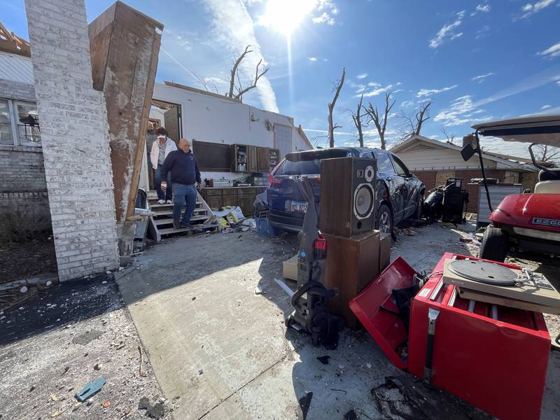 Aroma Township residents Tim and Karen Pinson exit through what was the garage of their home on Elmwood Drive on March 19, 2026 following the March 10 tornado. The couple took shelter in a closet just inside the garage doorway.