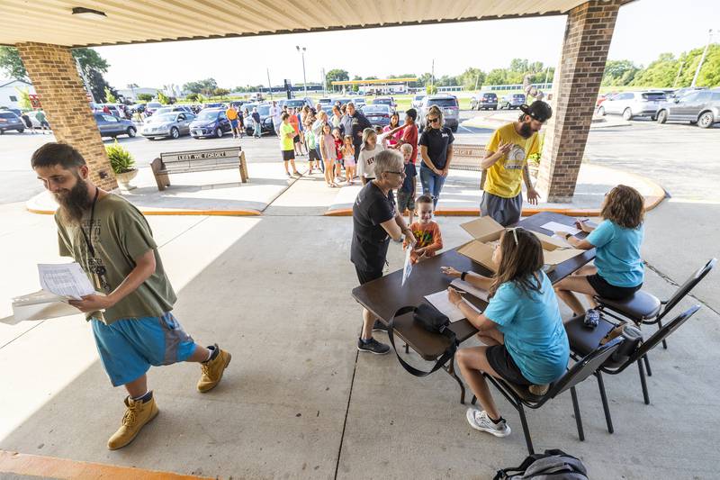 Pam Murphy with grandson Kayden Kilday, 7, checks in with Carrie Ramirez Thursday, Aug. 8, 2024 for the Tools for Schools distribution day in Dixon.