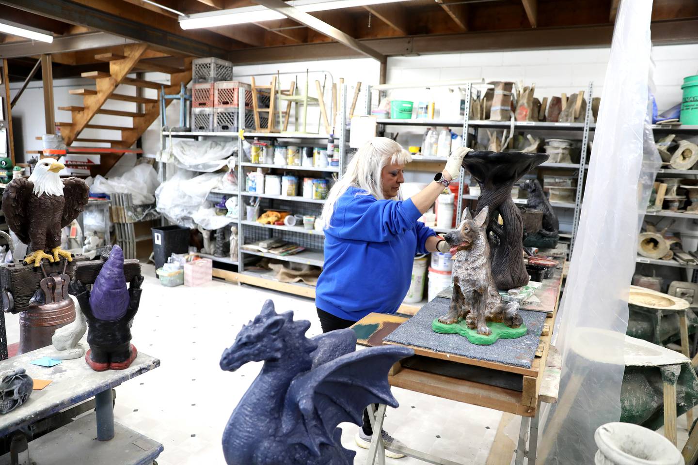 Valerie Neupert paints one of the pieces at Lion Concrete in Oswego. The shop, which was founded in 1925, is celebrating its 100th anniversary this year. The company, owned by Oswego couple Valerie and Scott Neupert, is now in its third generation.