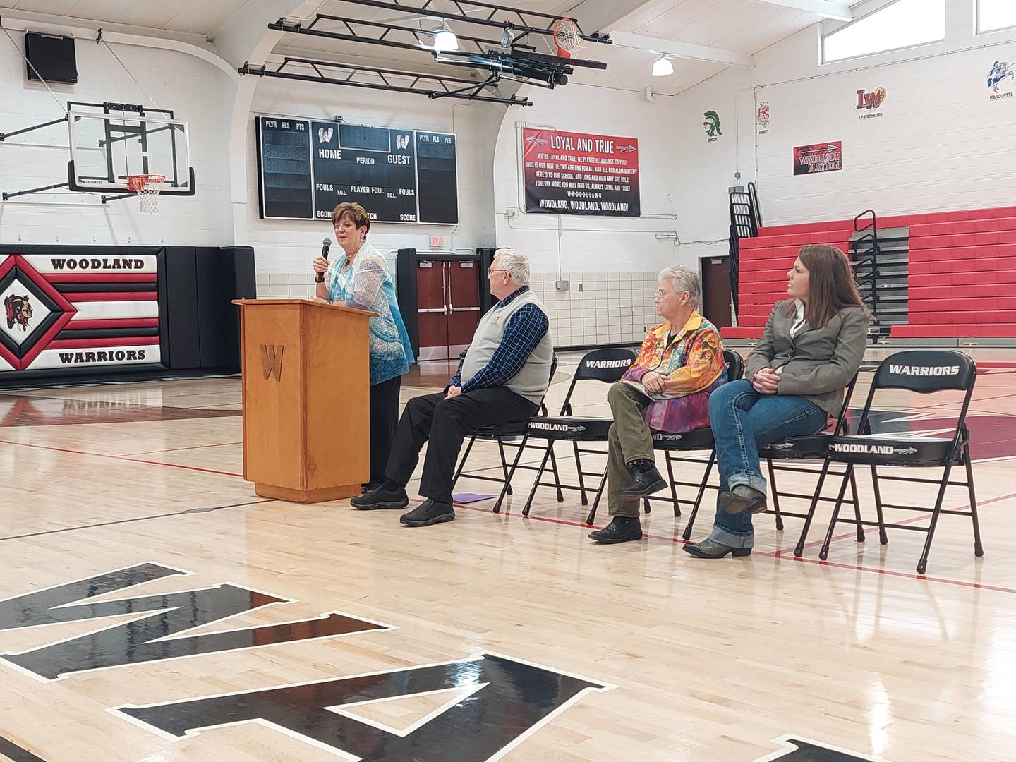 Woodland Hall of Fame inductee Dianne Conrad speaks to Woodland students, teachers and community members Friday, April 5, 2024, at the Warrior Dome as fellow hall of famers Dr. Alan Conrad, Joyce Cook and Jordan Wicks look on.