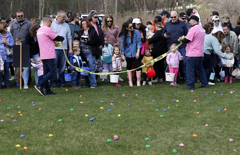 Voluteers remove the tape before starting the egg hunt on Saturday, April 19, 2025, during the Johnsburg Easter Egg Hunt at Sunnyside Memorial Park, in Johnsburg. Children hunted for 6,000 candy-filled eggs in three hunts divided by age group.
