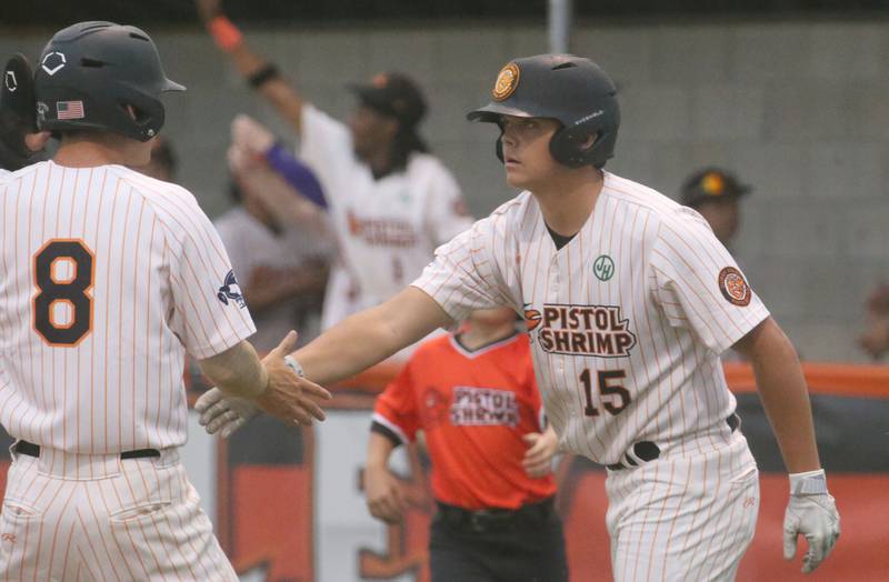 Illinois Valley Pistol Shrimp's Justin Lang hi-fives teammate Thomas Lynch after scoring the teams first run against the Normal Cornbelter during the Illinois Valley Pistol Shrimp home opener on Friday, May 30, 2025 at Schweickert Stadium in Peru.