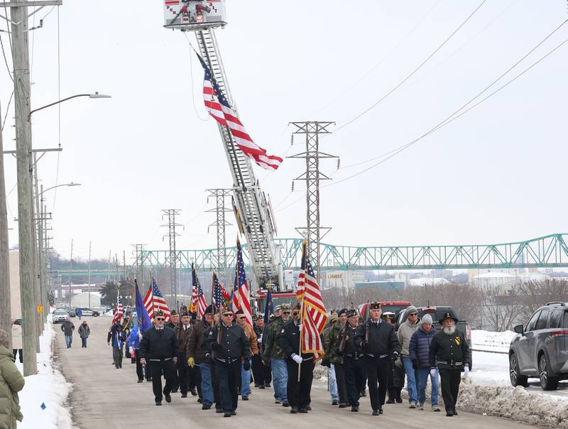 Veterans walk underneath the American Flag during the 46th annual Peal Harbor parade and Memorial service at the South Shore Boat Club in Peru.