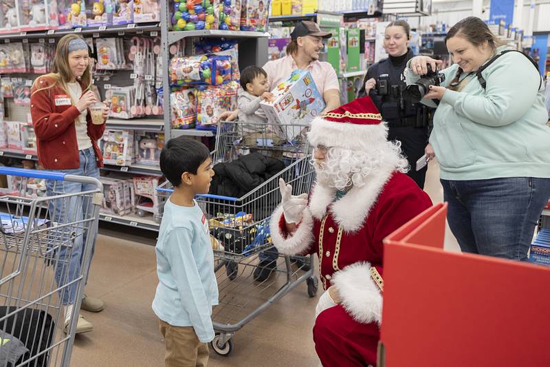 Santa quizzes Emilio on his math skills Saturday, Dec. 13, 2025, during the annual Shop with a Cop. The young whiz aced the addition problems he was asked.