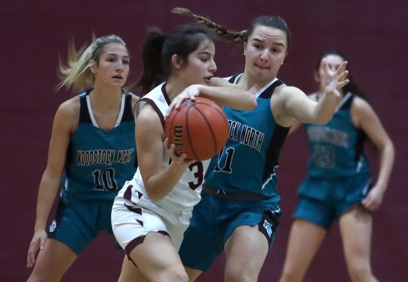 Marengo’s Keatyn Velasquez, center, moves the ball as Woodstock North’s Addison Rishling, left, and Gracie Zankle, right, defend in girls basketball at Marengo on Thursday.