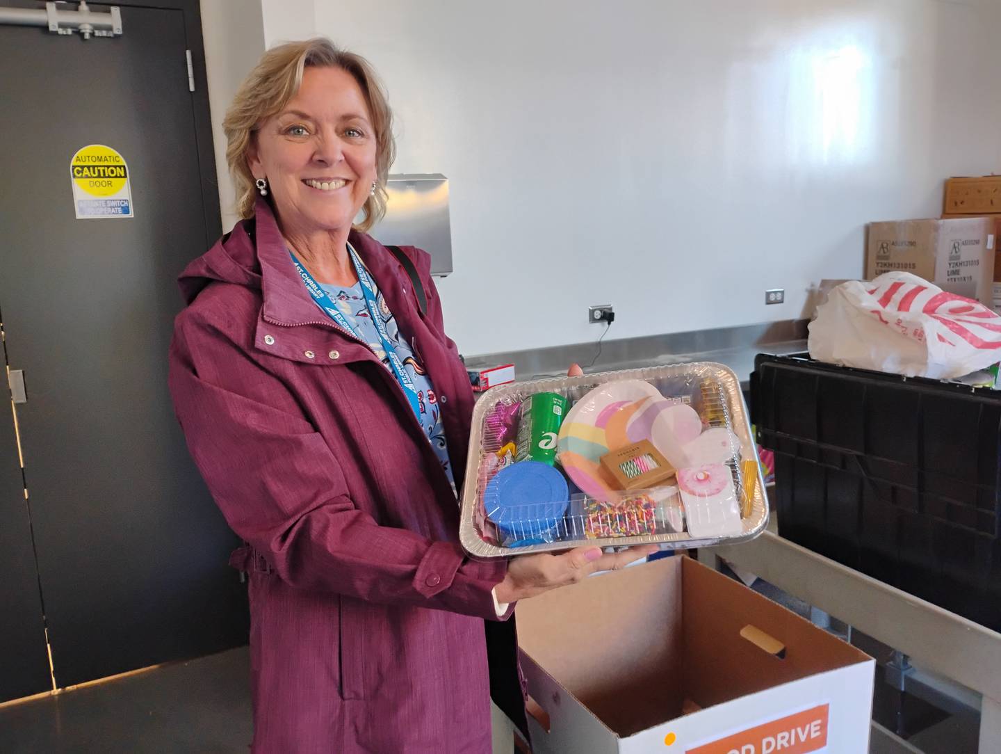 St. Charles Public Library spokeswoman Pam Salomone shows a birthday cake kit – among the many food items District 303 schools donated to the library's Community Cabinet – a food pantry within the library.