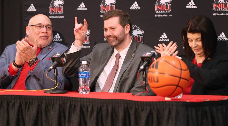 New Northern Illinois University men’s head basketball coach Matt Majkrzak gives the Huskie sign while flanked by NIU Vice President/Director of Athletics and Recreation, Sean Frazier, (left) and university president Lisa Freeman Tuesday, March 24, 2026, during a press conference in the Convocation Center to introduce Majkrzak at NIU in DeKalb.