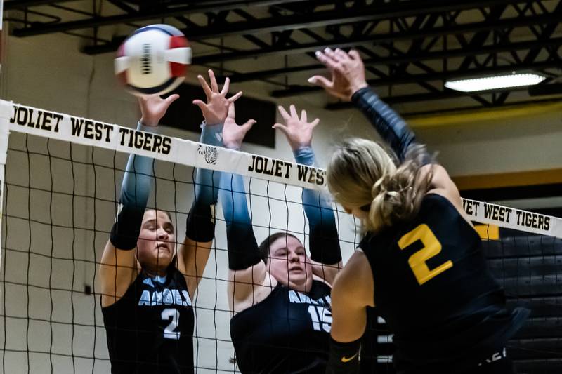 Joliet West's Lexie Grevengoed spikes as Joliet Catholic's Kate Duffy and Maggie Boehm attempt a block during a varsity volleyball home game at Joliet West Sept. 4, 2025.