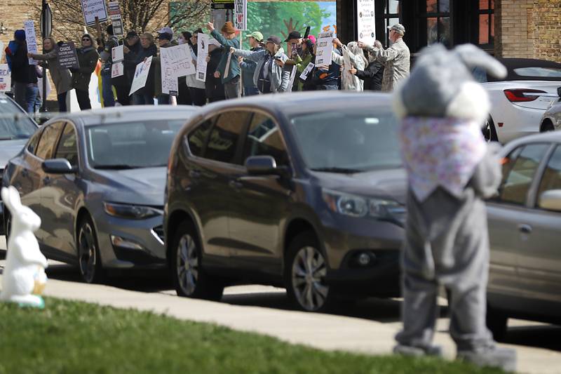 The Easter bunny in front of Anderson's Candy Shop competes with protesters for attention as they line U.S. Route 12 in Richmond to protest their discontent with President Donald Trump and his administration's policies on Saturday, April 19, 2025. Over 100, people took part in the Richmond protest. A second rally was held in Harvard later in the day.