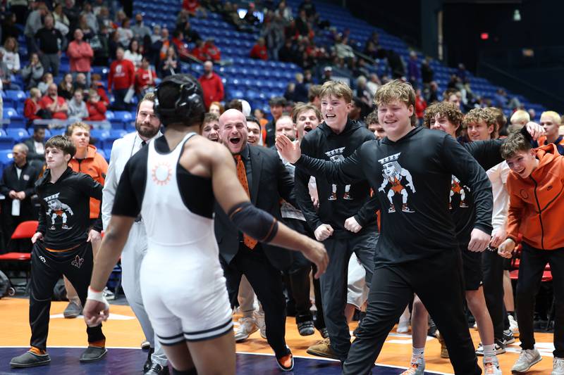 St. Charles East players and coaches rush to celebrate Isaac Lenard's 157-pound match win that secured the IHSA Class 3A Dual Team State third place victory over Oak Park-River Forest on Saturday, Feb. 28, 2026.