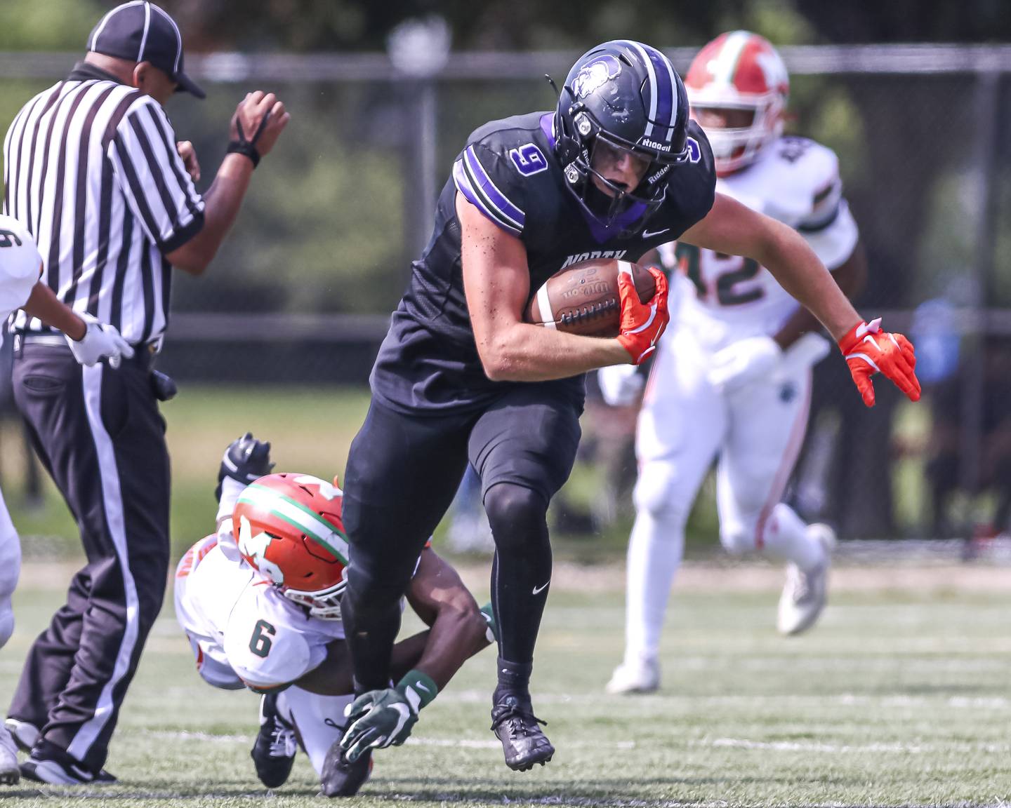 Downers Grove North's William Vala (9) shakes off a tackle attempt by Morgan Park's Anthony Marshall (6) during football game between Downers Grove North at Morgan Park Saturday, Aug 30, 2025  in Chicago.